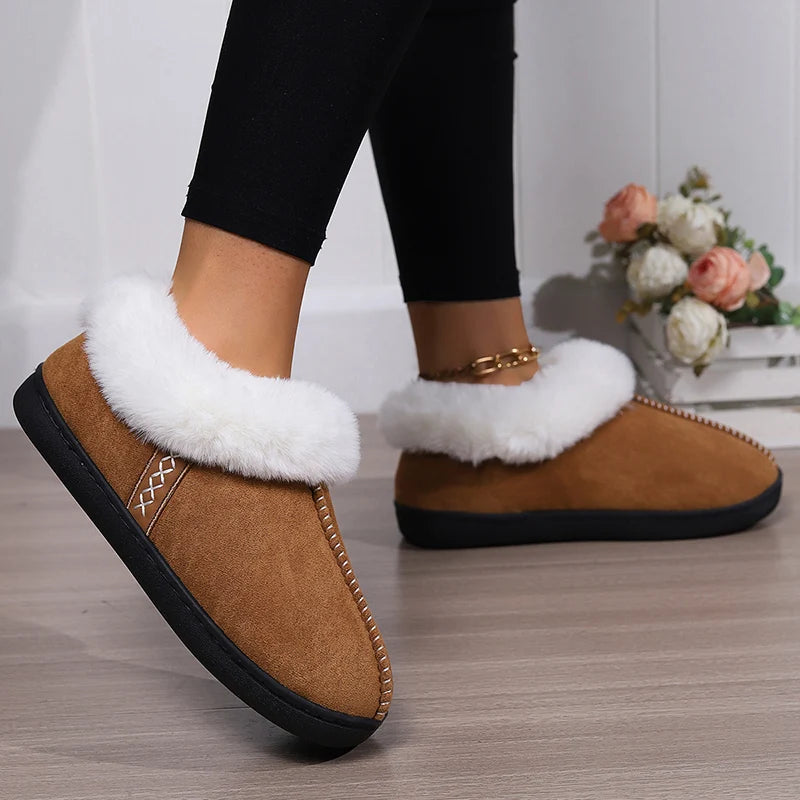 Brown slippers with white fur trim worn indoors on a wooden floor.