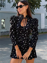 Woman wearing a black floral dress with puff sleeves outdoors.