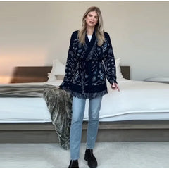 Woman wearing a dark patterned coat in a bedroom setting