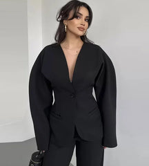 Woman wearing a black suit against a plain background