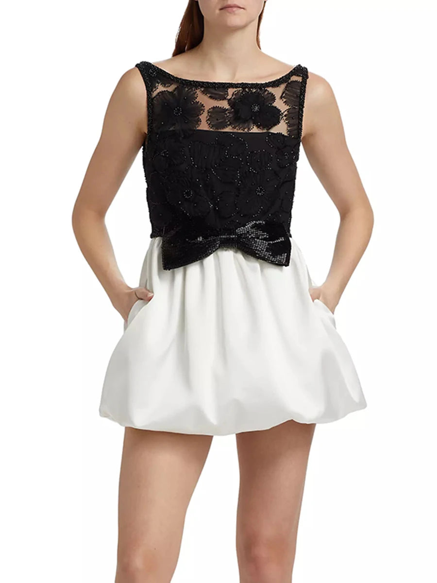 Black lace top and white skirt on a model against a white background