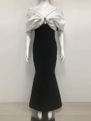 Mannequin wearing a black dress with a silver bow detail on a white background