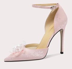 Pink high-heeled shoe with floral details on a white background