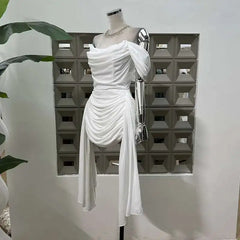 White draped dress on a mannequin with a geometric wall in the background