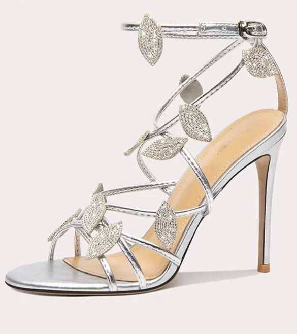 Silver high-heeled sandal with decorative straps on a white background