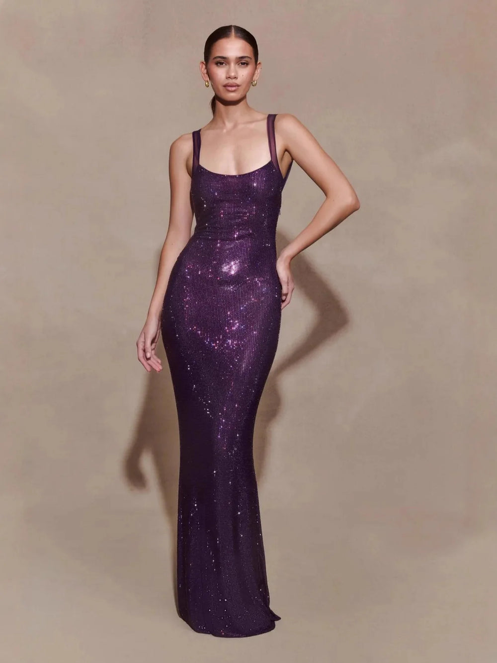 Woman wearing a purple sequin gown against a beige background