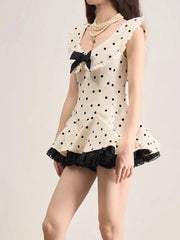 Woman wearing a polka dot dress with a bow tie on a plain background