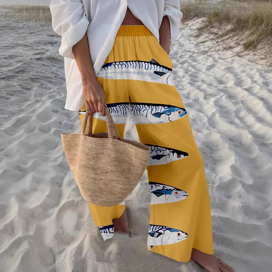 Person wearing a yellow skirt with fish pattern on a sandy beach