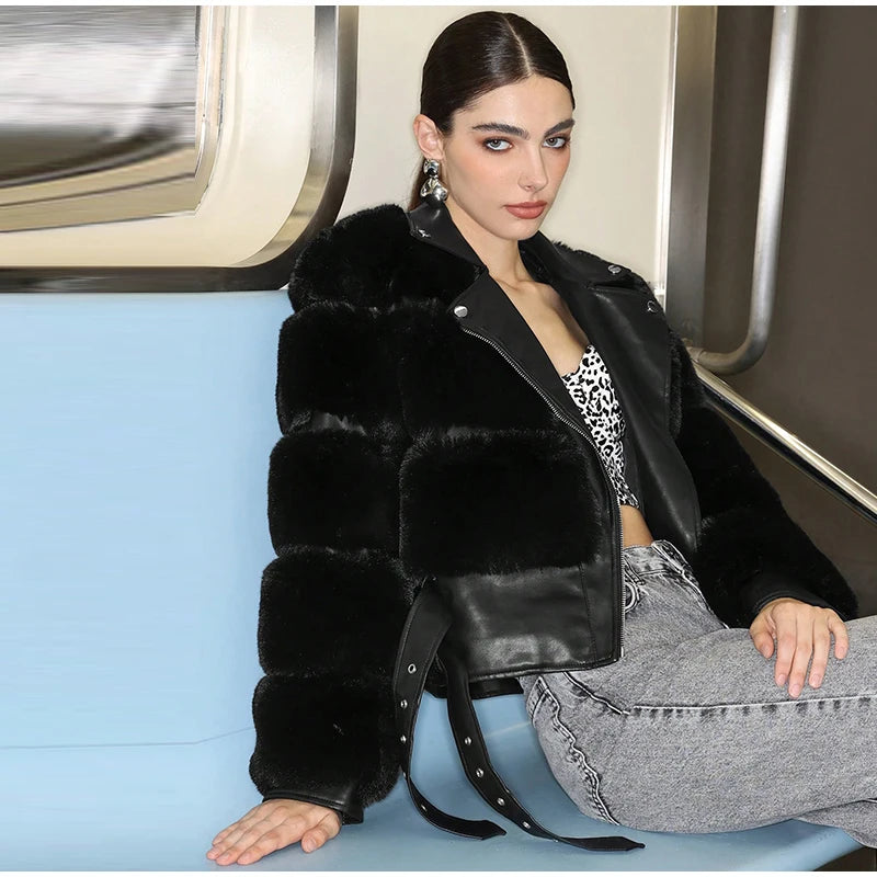 Woman wearing a black fur jacket and gray pants sitting on a blue seat.