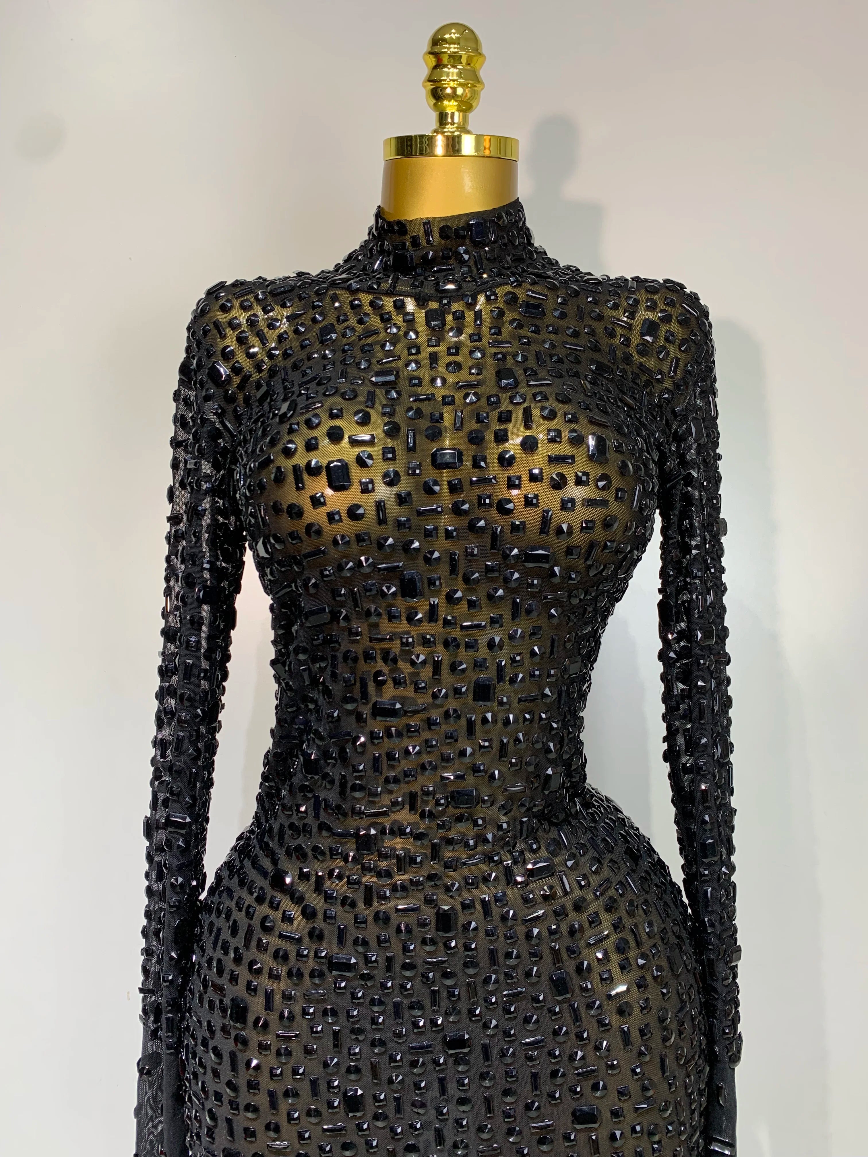Black beaded dress on a mannequin against a white background