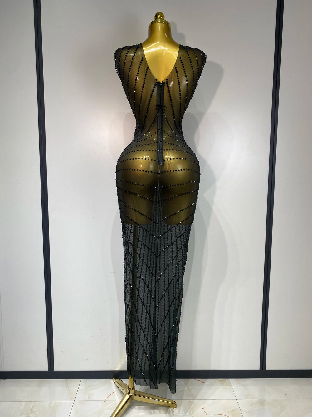 Black beaded evening gown on a mannequin against a plain background