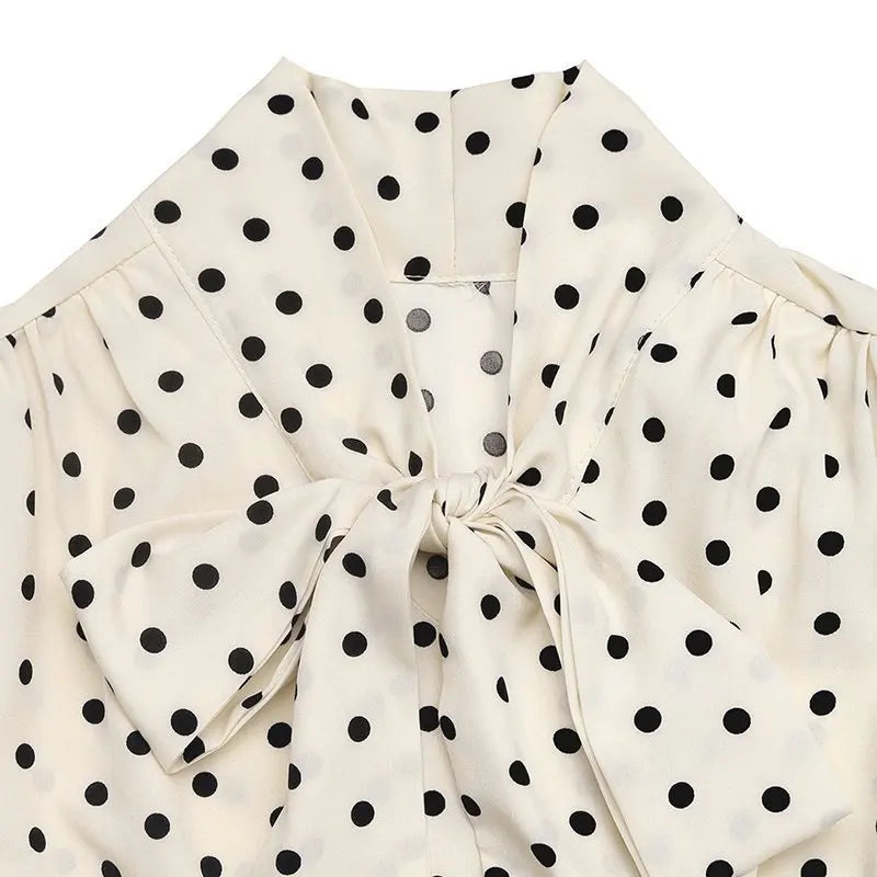 White blouse with black polka dots and a bow detail on a white background