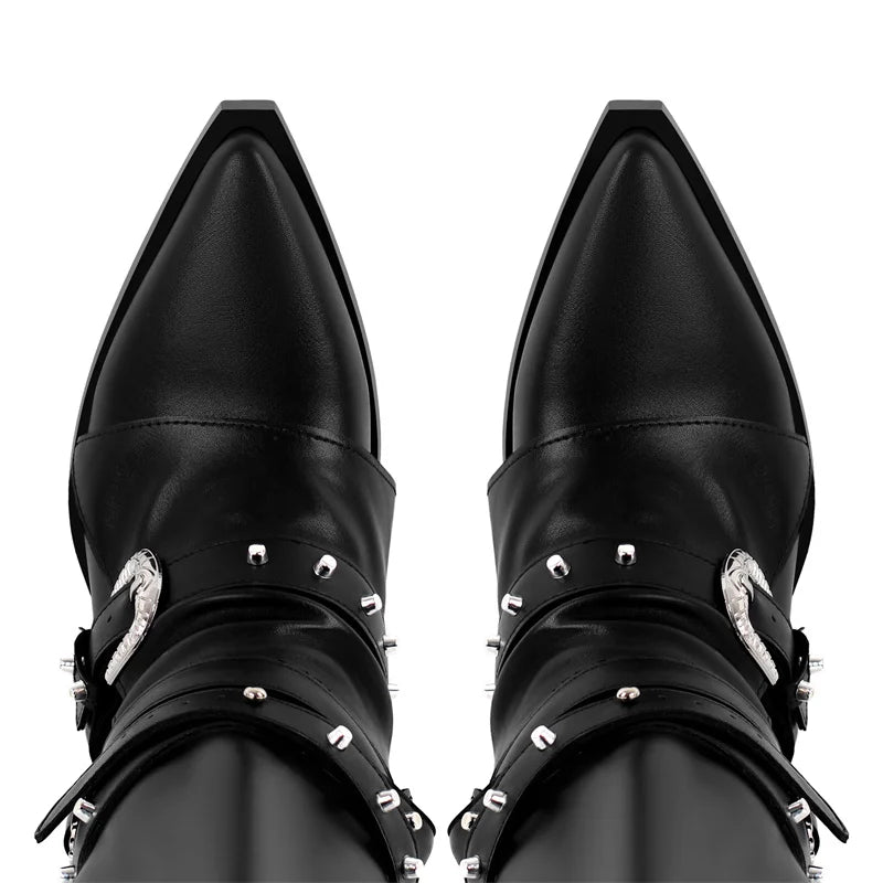 Close-up of the pointed toe area of black knee high boots with buckle and rivet embellishments.
