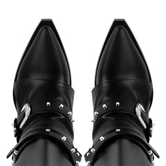 Close-up of the pointed toe area of black knee high boots with buckle and rivet embellishments.