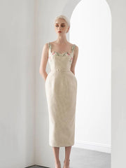 Woman wearing a beige dress with floral details in a minimalistic setting