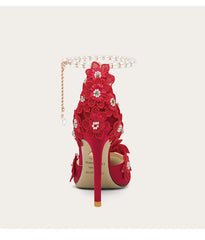 Red floral high-heeled shoe with decorative elements on a white background