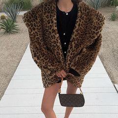 Person wearing a leopard print coat with a black handbag on a wooden path.