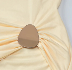 Close-up of a beige fabric with a metallic brooch on a light gray background