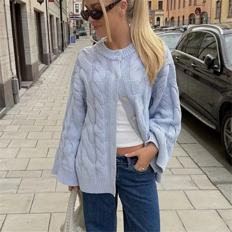 Woman wearing a light blue cable knit cardigan on a city street.