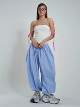 Woman wearing a white strapless top and blue striped pants on a plain background