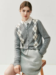 Woman wearing a gray argyle sweater over a white shirt on a light background