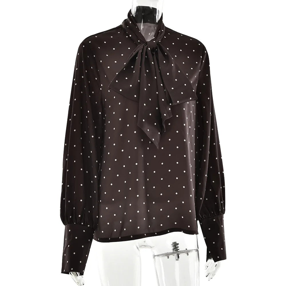 Black blouse with white polka dots and a tie neckline on a mannequin against a white background