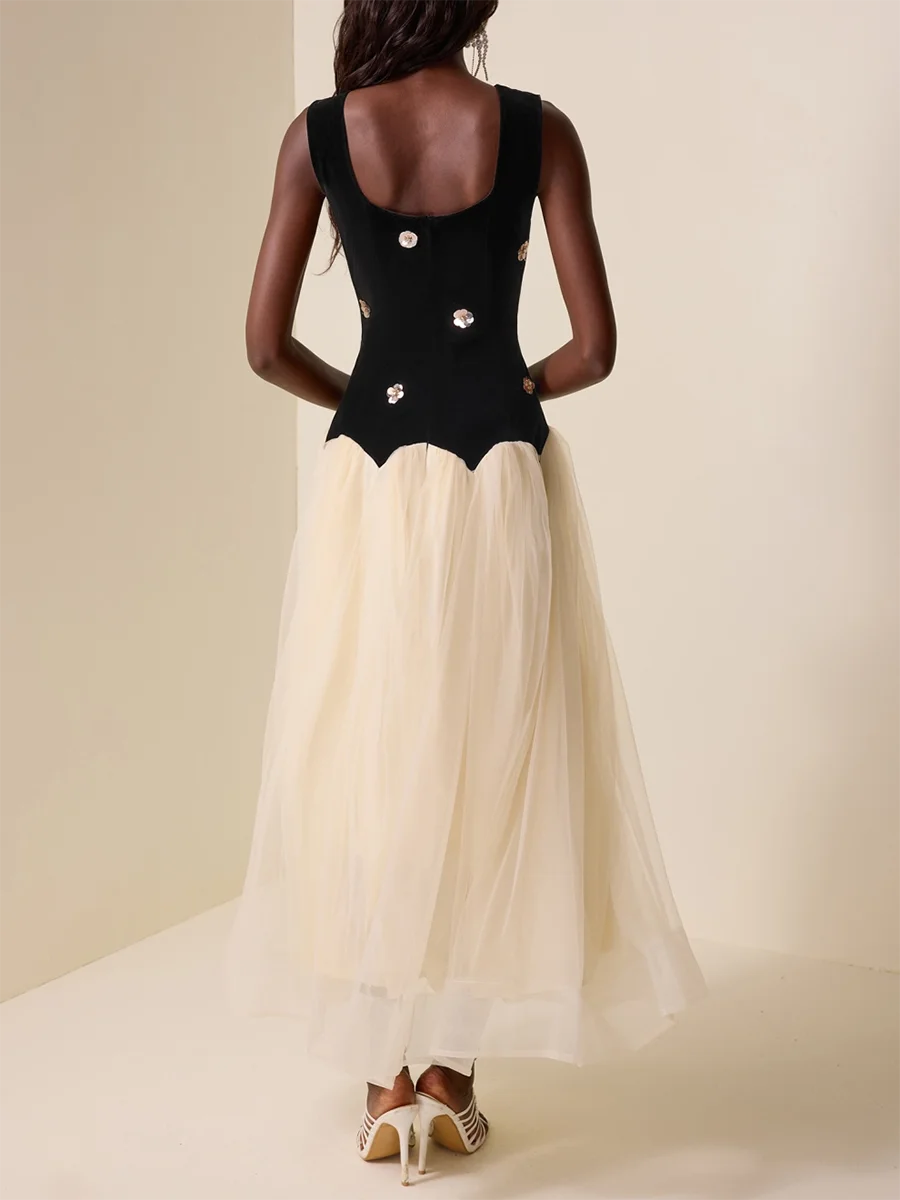 Woman wearing a black top and beige skirt against a plain background