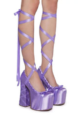 Purple platform heels with ribbon straps on a white background