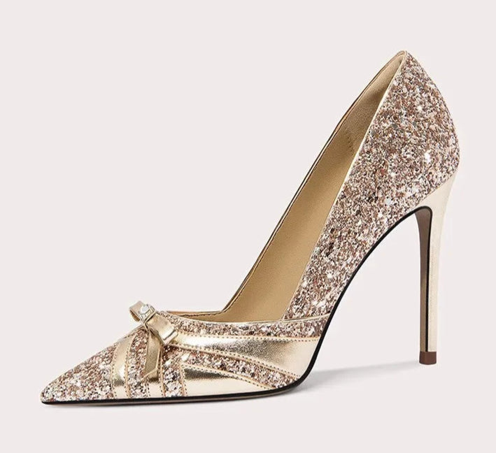 Gold glitter high-heeled shoe with a bow on a white background