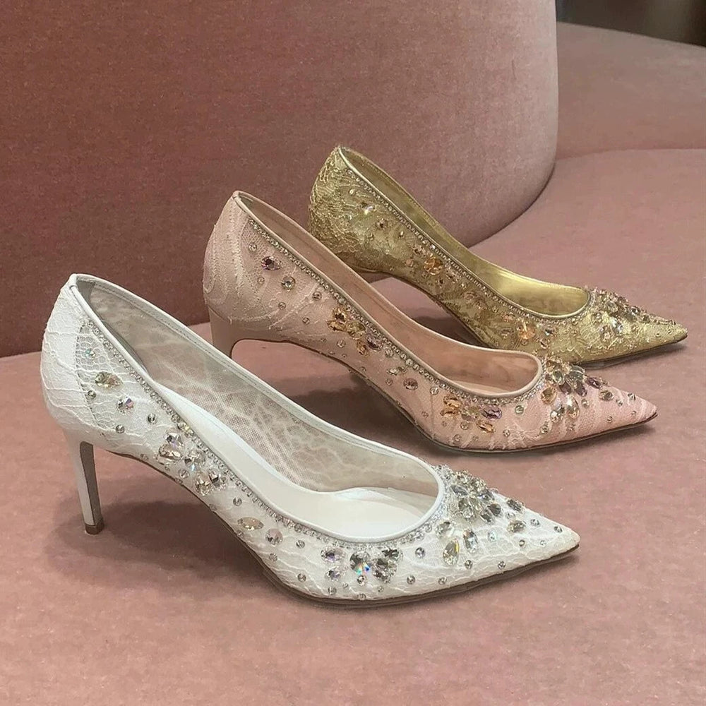 Pair of embellished high-heeled shoes on a pink surface