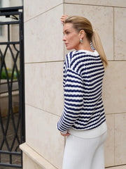 Woman wearing a blue and white striped sweater against a beige wall.