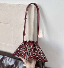 Red handbag with black and white pattern held by a person against a neutral background