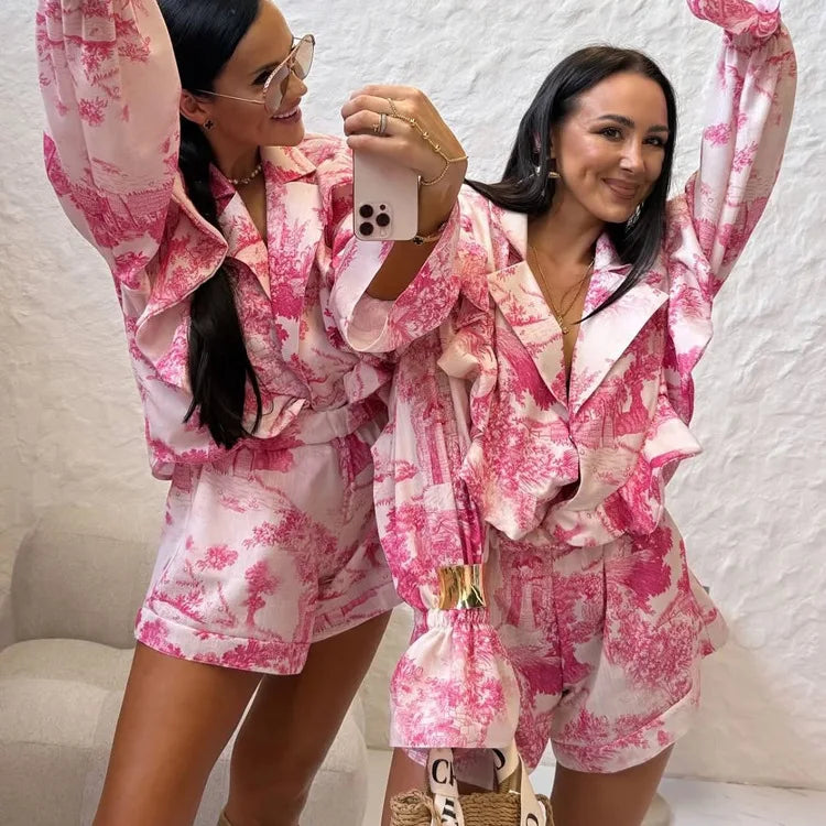 Two women in matching pink and white floral outfits taking a selfie.