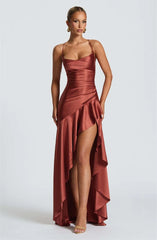 Woman wearing a rust-colored evening gown with a high slit on a white background