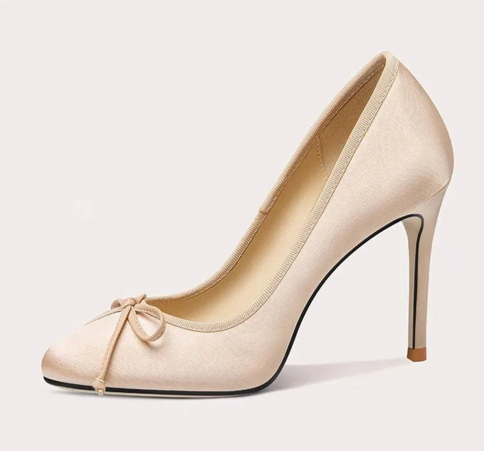 Beige high-heeled shoe with a bow on a light gray background