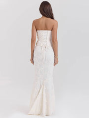 Woman wearing a strapless white lace dress on a plain background