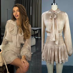 Woman wearing a beige dress with a matching blouse on a mannequin against a blue background.