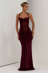 Woman wearing a burgundy evening gown against a plain background