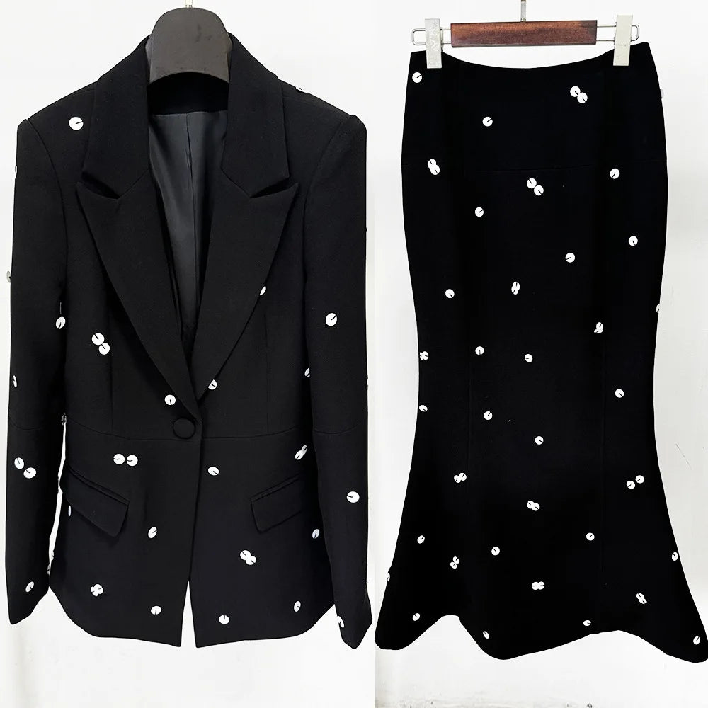 Black blazer and skirt with white embellishments on hangers against a white background