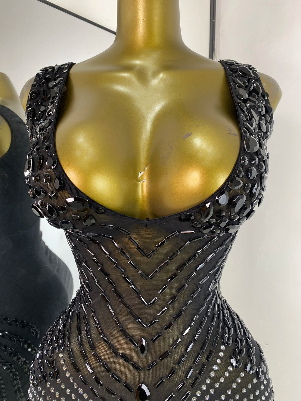 Close-up of the embellished neckline on a black sheath mini dress.