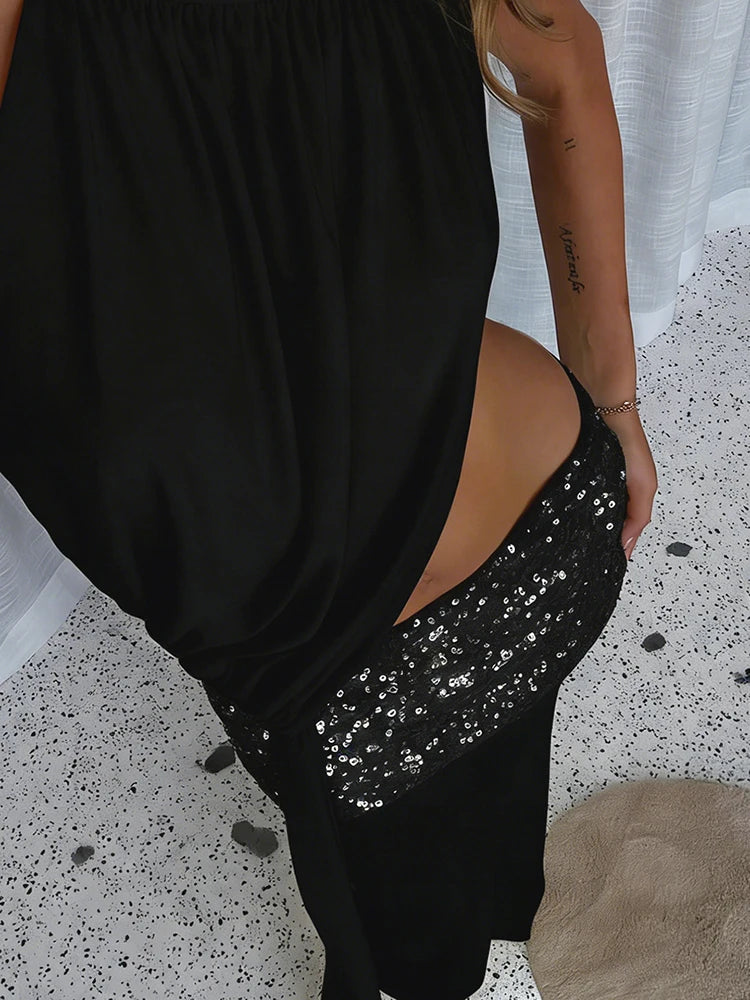 Person wearing a black dress with a sequin panel on a speckled floor.