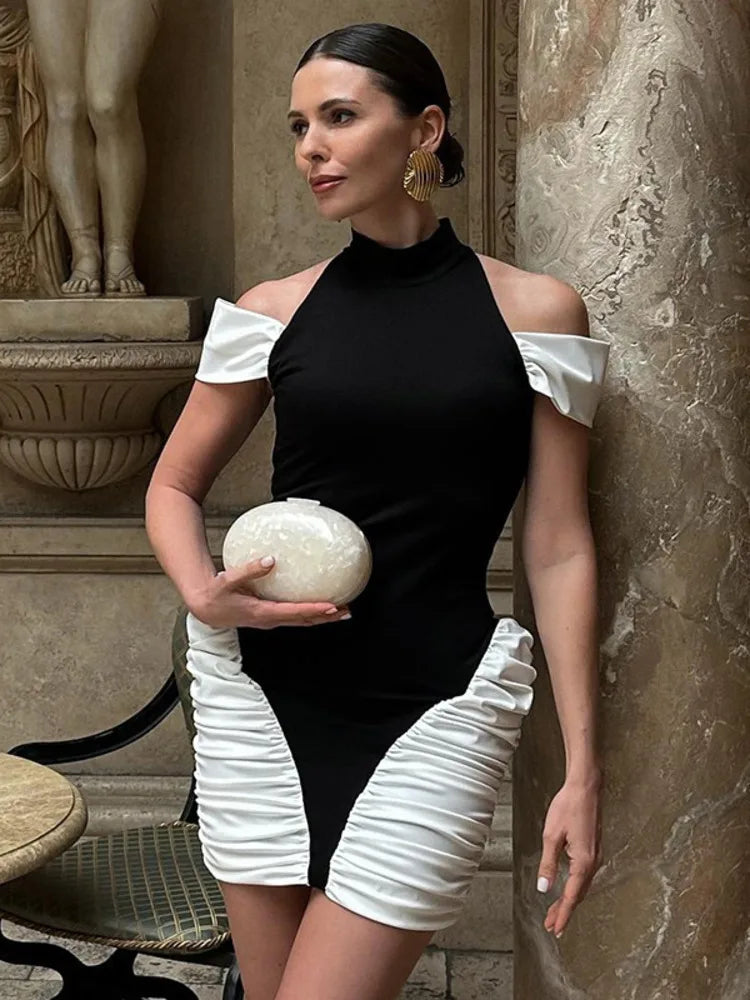 Woman in a black and white dress holding a decorative object in an elegant setting.