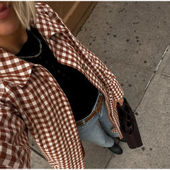 Person wearing a brown and white checkered shirt on a sidewalk.