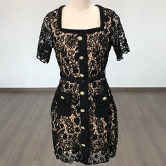 Black lace dress on a mannequin against a white wall.