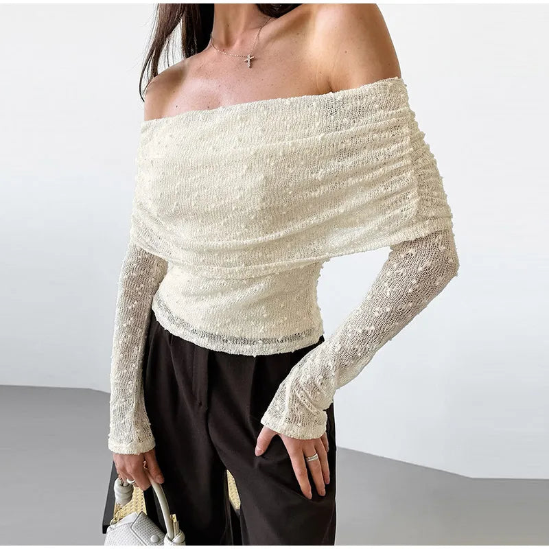 Woman wearing a white off-shoulder top with long sleeves on a plain background