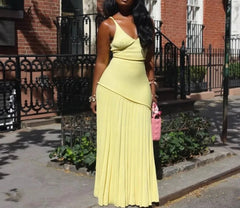 Woman in a yellow dress holding a pink bag on a city street.