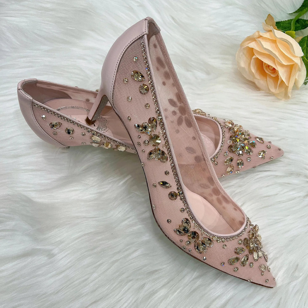 Pink high-heeled shoes with embellishments on a white fur surface with a rose.