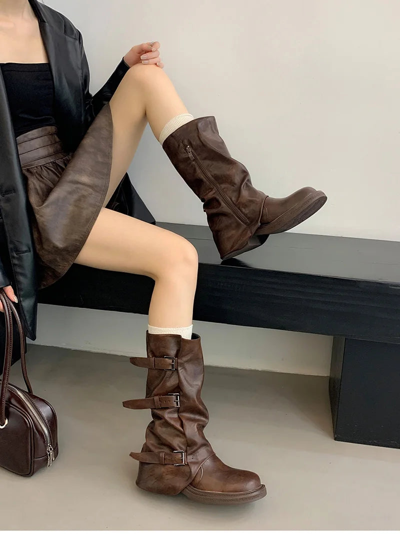 Person wearing brown knee-high boots sitting on a bench.