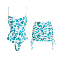 White one-piece swimsuit with abstract blue and green dots and a matching ruched skirt.