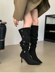 Black knee-high boots with high heels worn by a person in a neutral setting.